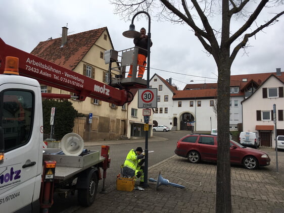 Die alte Straßenlampe mit konventionellen Leuchtmitteln wurde bereits abgebaut, die neue LED-Leuchte wird im Austausch montiert.