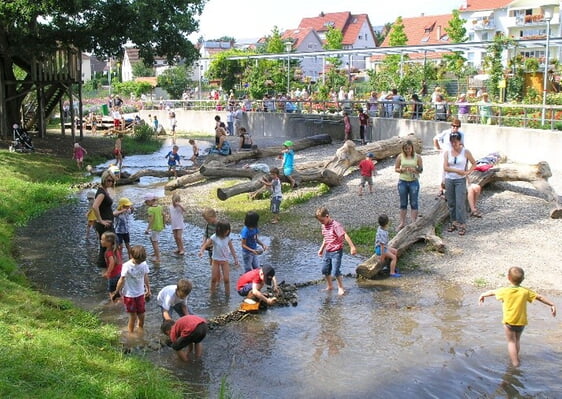 Spielende Kinder am „Strand“ des Katzentalbaches im Park