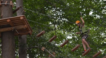 Kind läuft im Kletterwald Weinsberg über eine Hängebrücke in den Bäumen