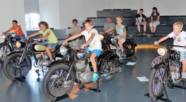 Kinder sitzen im NSU Museum auf Motorräder
