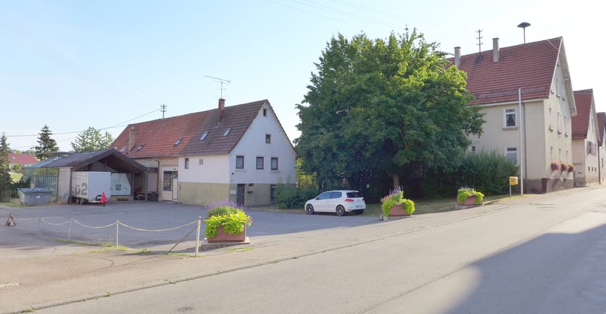 Es geht um die beiden Gebäude vorne an der Straße und den Platz, der auf dem Bild erkennbar ist